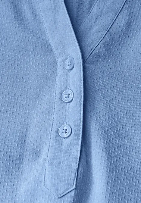 Hellblauer Stoff mit drei Knöpfen und feiner Struktur.